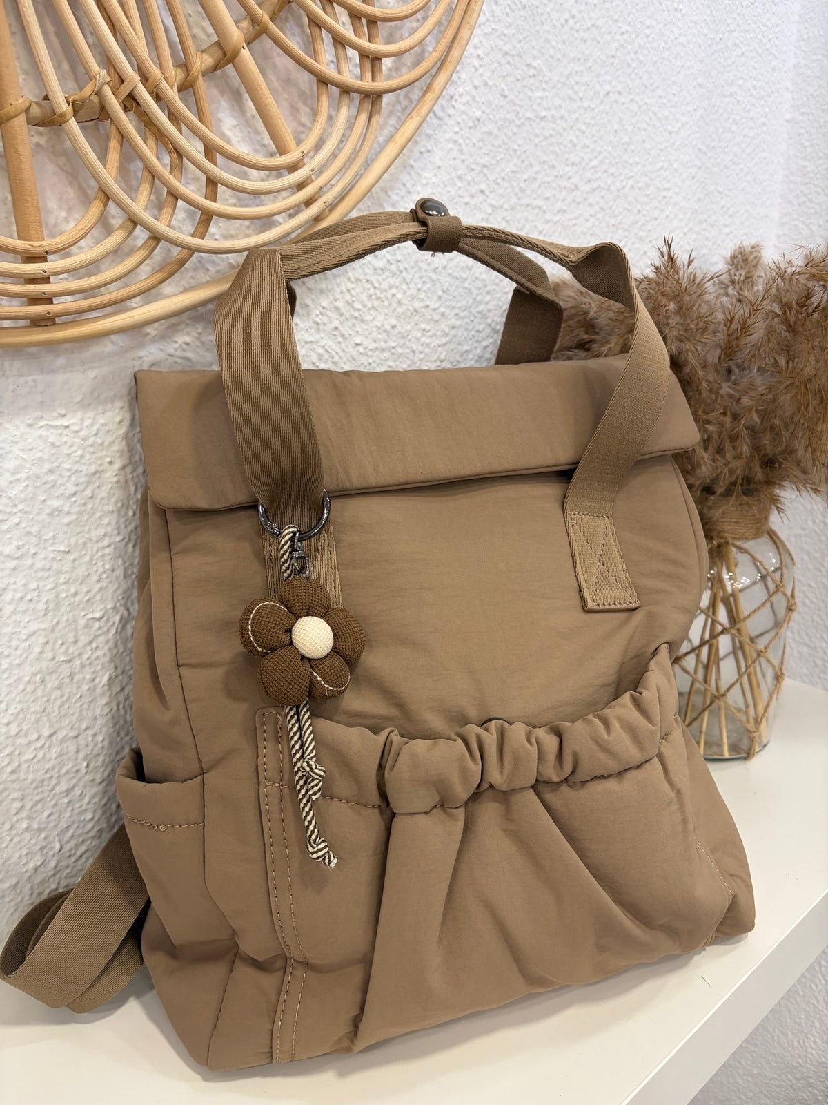 Mochila camel de nylon con adorno de flor y correa trenzada